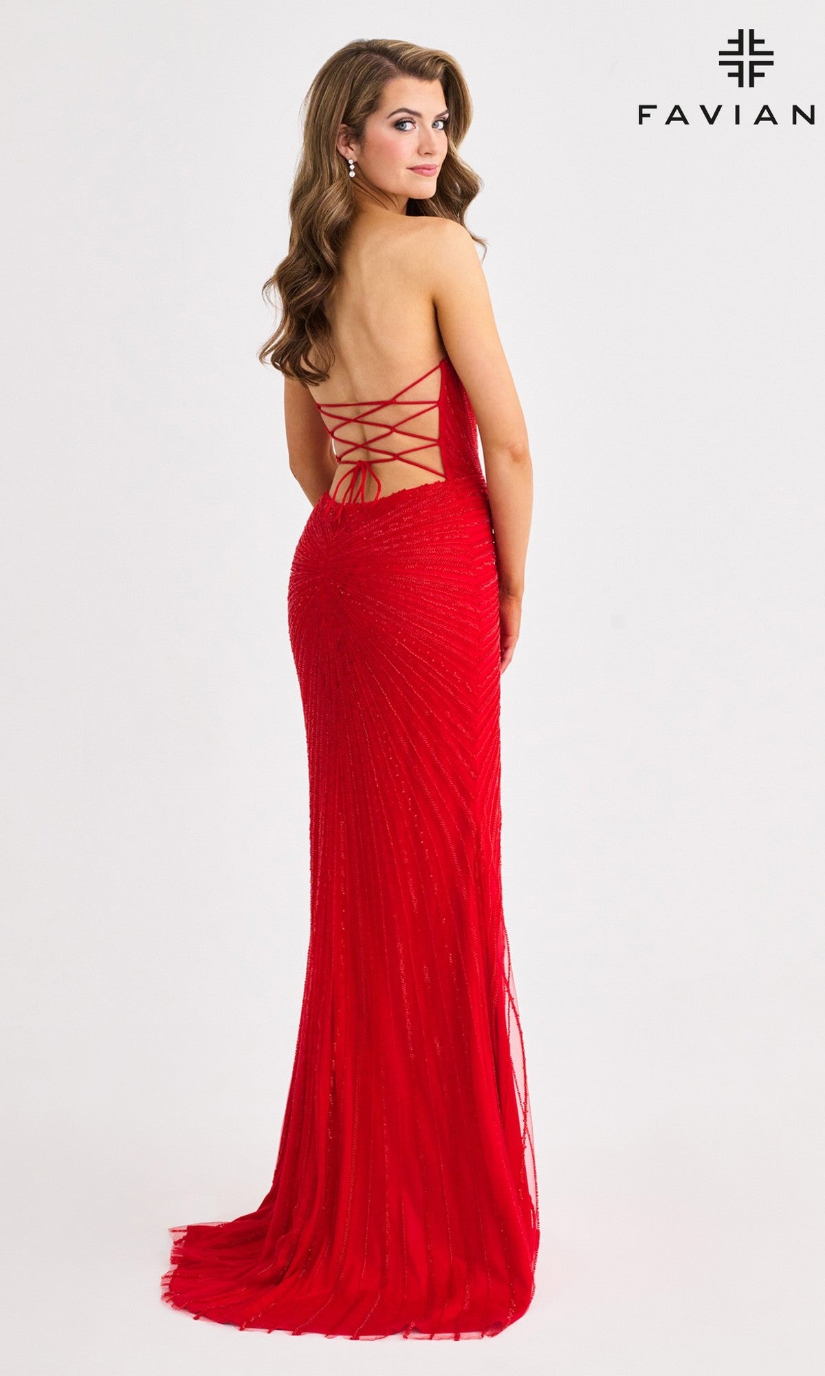 A woman models the Faviana 11410 long prom dress in red, featuring criss-cross lace-up detail. She stands looking over her shoulder against a plain white background with the